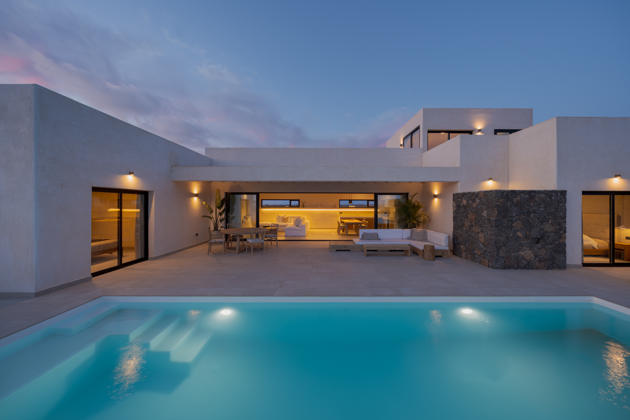 Villa Victorina at twilight with illuminated pool, covered terrace and modern architecture